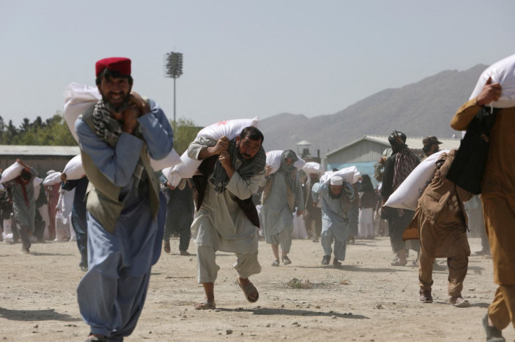 Afghan people carry sacks of rice, given out as part of humanitarian aid sent by China to Afghanistan, at a distribution centre in Kabul, Afghanistan, April 7, 2022.