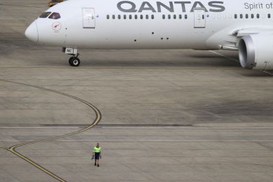 A ground worker walking near a Qantas plane is seen from the international terminal at Sydney Airport, in Sydney, Australia, Nov. 29, 2021. 
