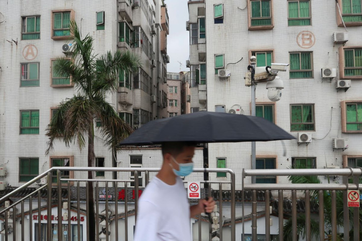 A man holding an umbrella walks on a pedestrian bridge by surveillance cameras, near Caopu in Shenzhen's Luohu district, Guangdong province, China July 5, 2022.