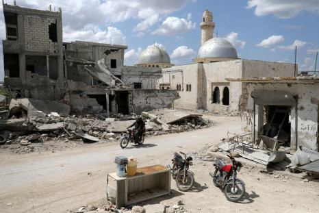 Men ride a motorbike past a stall selling diesel, water and soft drinks near damaged buildings in the rebel-held town of Nairab, in northwest Syriaâs Idlib region, Syria April 17, 2020. 