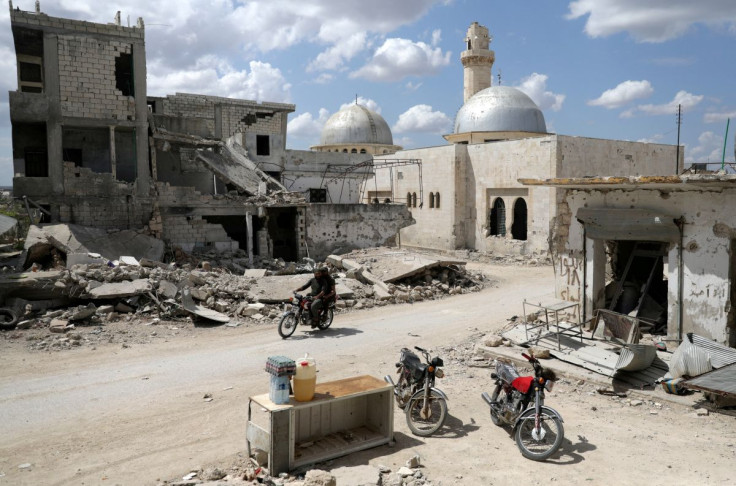 Men ride a motorbike past a stall selling diesel, water and soft drinks near damaged buildings in the rebel-held town of Nairab, in northwest Syriaâs Idlib region, Syria April 17, 2020. 