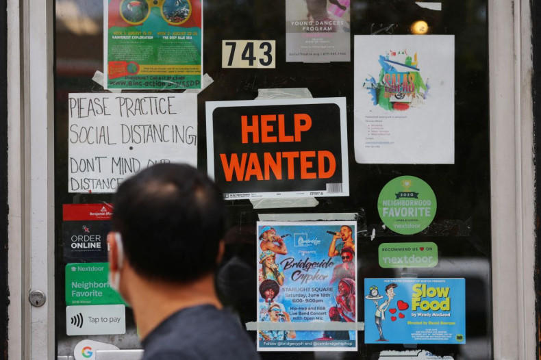 A pedestrian passes a "Help Wanted" sign in the door of a hardware store in Cambridge, Massachusetts, U.S., July 8, 2022.   