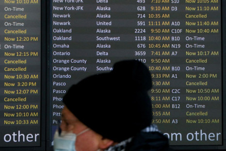 A traveler walks past a screen showing dozens of flights listed as cancelled or delayed at Seattle-Tacoma International Airport (Sea-Tac) in Seattle, Washington, U.S. December 27, 2021.  