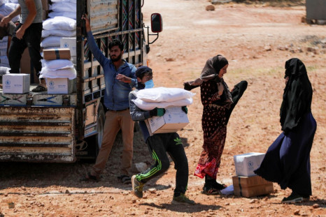 A worker holds bags and a box of humanitarian aid in the opposition-held Idlib, Syria June 9, 2021. Picture taken June 9, 2021. 
