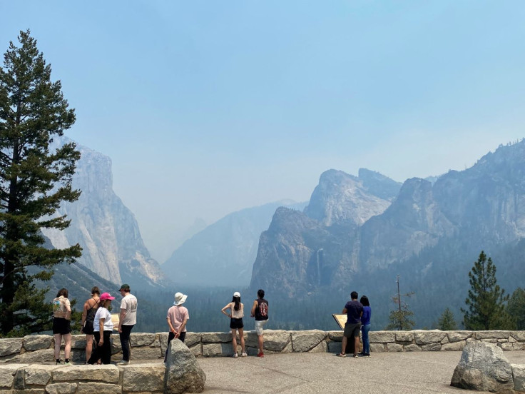 Visitors check out the view from the east end of the Wawona Tunnel into Yosemite Valley, showing three major landmarks, from the left, El Capitan, Half Dome and Bridalveil Fall, obscured by thick smoke in the area from the wildfire burning to the south in