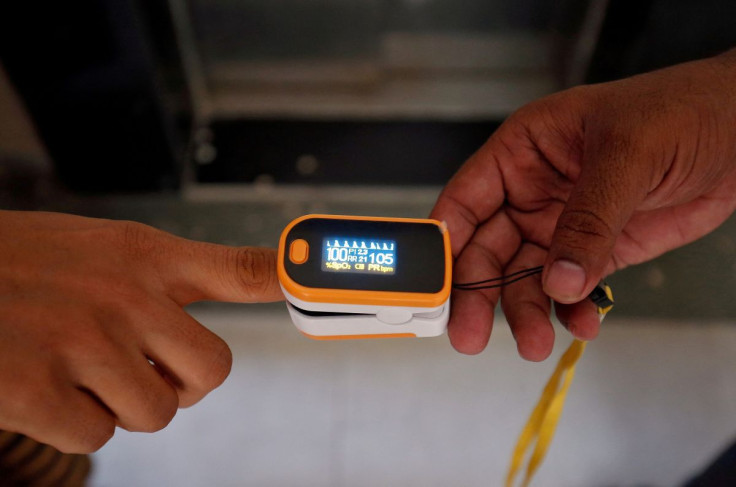 A medical worker (R) puts a pulse oximeter on a woman's finger to check her oxygen level during a door-to-door survey for the coronavirus disease (COVID-19) amidst its spread in Ahmedabad, India June 26, 2020. 