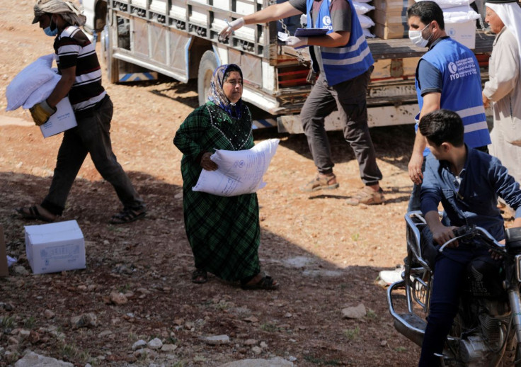  An internally displaced Syrian woman walks as she holds a bag of humanitarian aid in the opposition-held Idlib, Syria June 9, 2021. Picture taken June 9, 2021. 