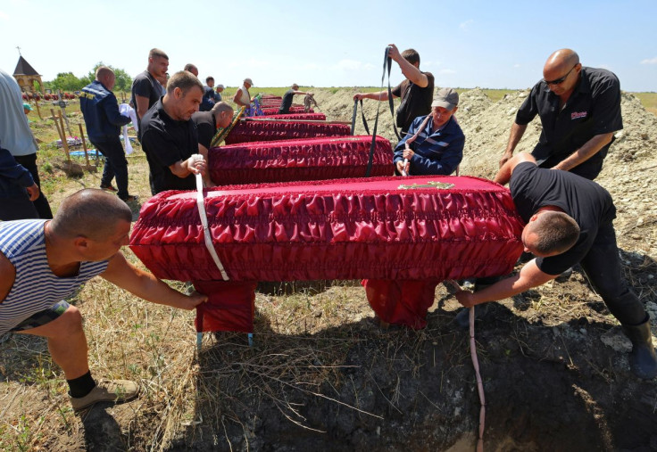 Workers prepare to lower coffins during a funeral for 58 unidentified soldiers of the self-proclaimed Luhansk People's Republic who were killed in 2022 during Ukraine-Russia conflict, in Luhansk, Ukraine July 12, 2022.