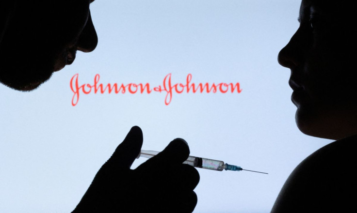 People pose with syringe with needle in front of displayed Johnson & Johnson logo in this illustration taken, December 11, 2021. 