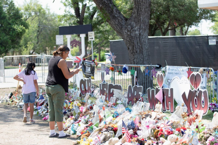 A woman uses her mobile phone at a memorial outside Robb Elementary School the day after a video was released showing the May shooting inside the school in Uvalde, Texas, U.S., July 13, 2022.    