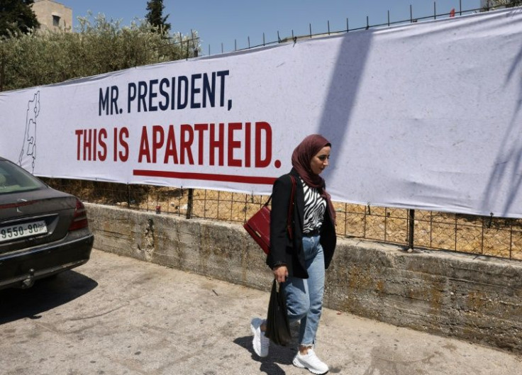 A woman walks past a poster, part of a campaign organised by Israeli rights group B'Tselem, in the West Bank city of Bethlehem, where Biden is due to meet Palestinian president Mahmud Abbas on Friday