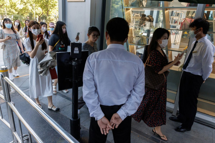 Security guards check the health code app of people entering a business area before office hours, following a coronavirus disease (COVID-19) outbreak, in Beijing, China, July 14, 2022.