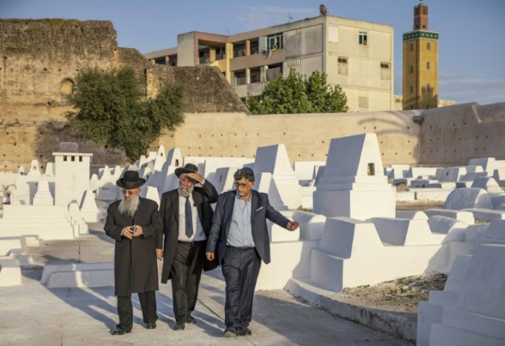 Members of the Jewish community pass graves at a Jewish cemetery in Morocco's northern city of Meknes on May 18, 2022
