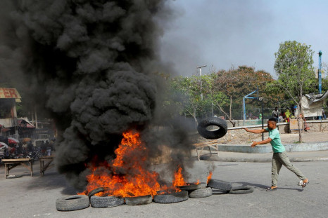 A demonstrator throws a tyre on a burning road block as anger mounted over fuel shortages that have intensified as a result of gang violence, in Port-au-Prince, Haiti, July 13, 2022. 