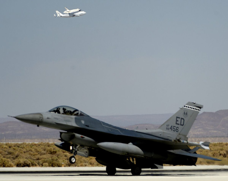 An F-16 fighter jet is seen in the foreground as the space shuttle Endeavour makes a flyby before landing at Edwards Air Force Base in California, September 20, 2012. 