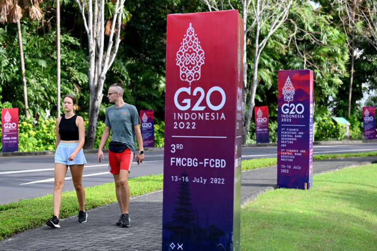 Foreign tourists walk past banners of the G20 summit near a venue for the G20 Finance Ministers Meeting in Nusa Dua on Indonesia's resort island of Bali, on July 14, 2022. Sonny Tumbelaka/Pool via REUTERS