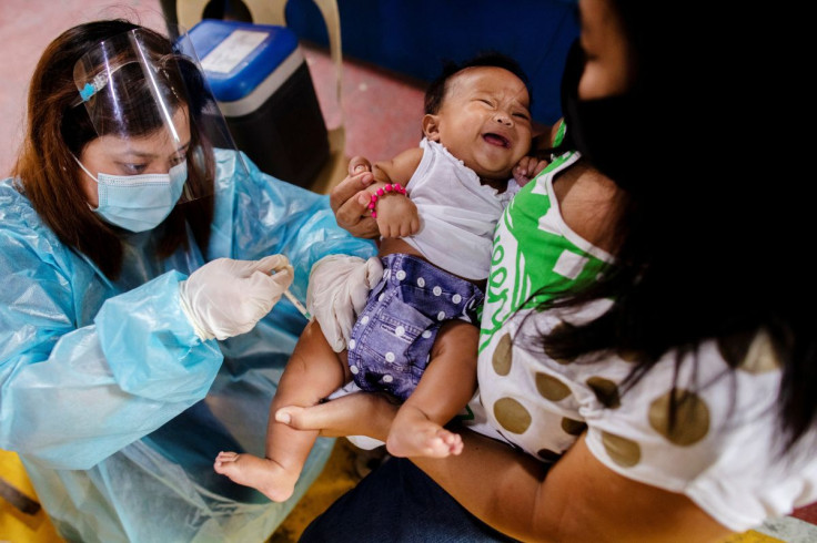 A nurse wearing personal protective equipment (PPE) for protection against the coronavirus disease (COVID-19) gives routine vaccines to a baby held by his mother in a local health center in Manila, Philippines January 27, 2021.