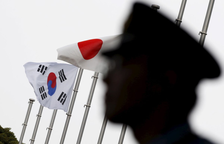 A police officer stands guard near Japan and South Korea national flags at hotel, where South Korean embassy in Japan is holding the reception to mark the 50th anniversary of normalisation of ties between Seoul and Tokyo, in Tokyo  June 22, 2015. 