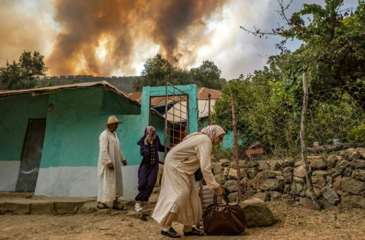 People evacuate a house as a wild forest fire rages in northern Morocco