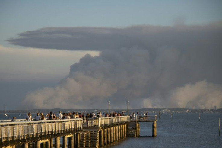 Tourists watch dark smoke from the pier in Andernos-les-Bains, France due to a wildfire near La Teste in the southwest of the country