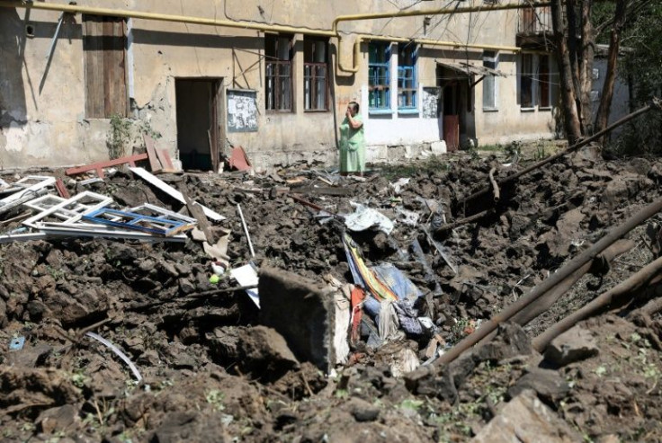 A woman stands in front of her destroyed house following a Russian airstrike in Toretske, a town in Ukraine's Donetsk region, on July 17, 2022