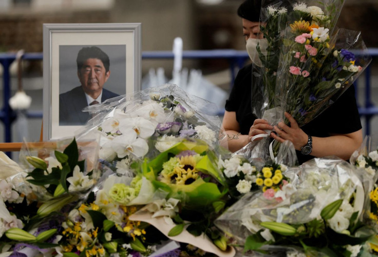 A mourner offers flowers next to a picture of late former Japanese Prime Minister Shinzo Abe, who was shot while campaigning for a parliamentary election, on the day to mark a week after his assassination at the Liberal Democratic Party headquarters, in T