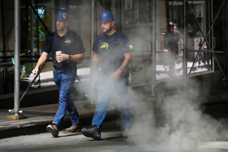 Workers walk through a cloud of steam during a heatwave in New York