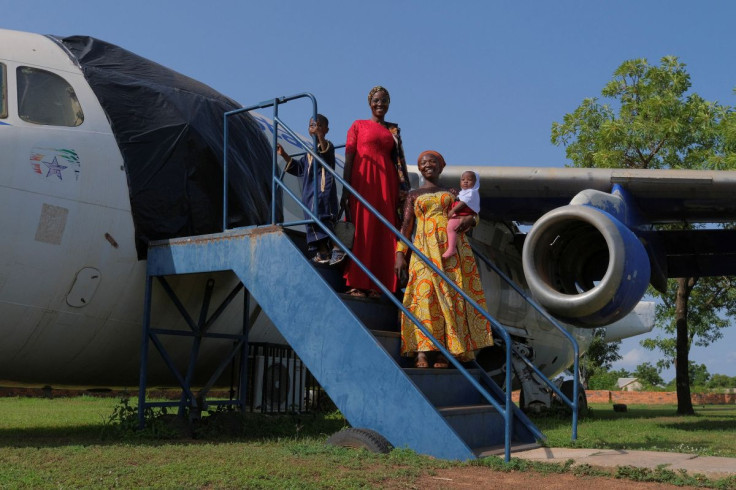 A family touring the Red Clay studio facility of Ghanaian artist Ibrahim Mahama, 35, pose for a photograph by an airplane, in Tamale, Ghana, July 15, 2022. 