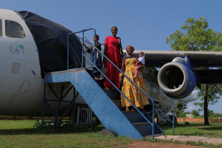 A family touring the Red Clay studio facility of Ghanaian artist Ibrahim Mahama, 35, pose for a photograph by an airplane, in Tamale, Ghana, July 15, 2022.