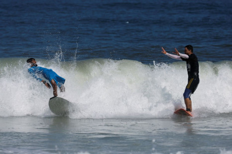 Palestinian surfer Mohammad Abu Ghanim and another surfer surf in the sea, in Gaza City July 12, 2022. 