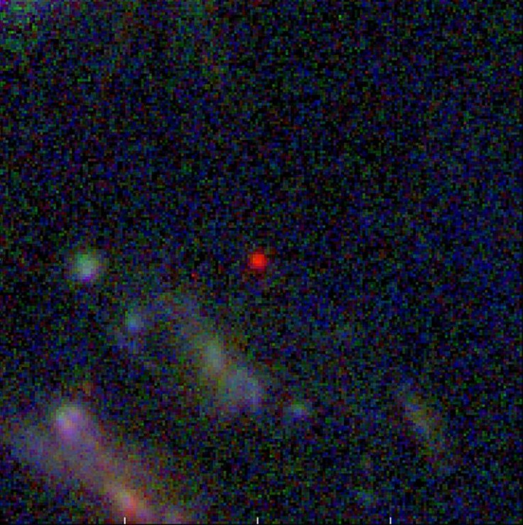 When translated from infrared into the visible spectrum, the galaxy appears as a blob of red with white in its center as part of a wider image of the distant cosmos
