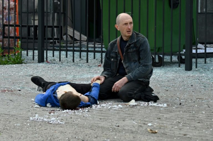 A relative kneels by the body of a teenager who died in a Russian missile strike at a bus stop in Kharkiv