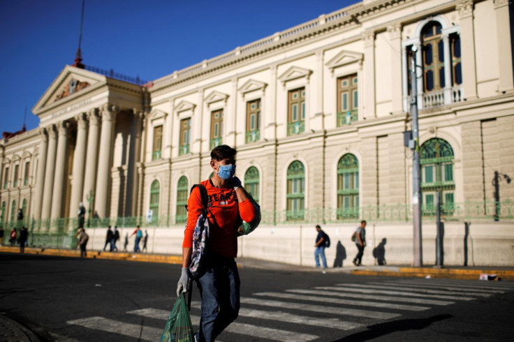 A man walks after buying groceries in front of the National Palace after El Salvador's President Nayib Bukele ordered home quarantine for 30 days throughout the country as the government undertakes steadily stricter measures to prevent a possible spread o