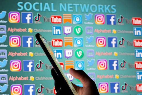 Woman with smartphone is seen in front of displayed social media logos in this illustration taken, May 25, 2021. 