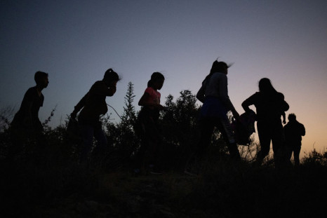 Migrants from Central and South America walk along a dirt trail after crossing the Rio Grande river into the United States from Mexico, in Roma, Texas, U.S., July 16, 2022. 