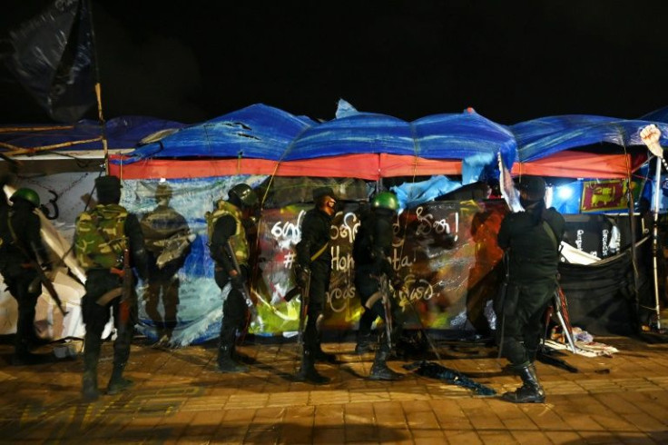 Sri Lankan security forces tear down temporary structures set up by anti-government protesters at the site of the protest camp in front of Colombo's Presidential Secretariat