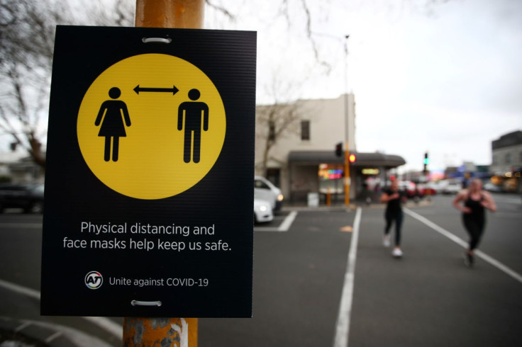 People jog past a social distancing sign on the first day of New Zealand's new coronavirus disease (COVID-19) safety measure that mandates wearing of a mask on public transport, in Auckland, New Zealand, August 31, 2020.