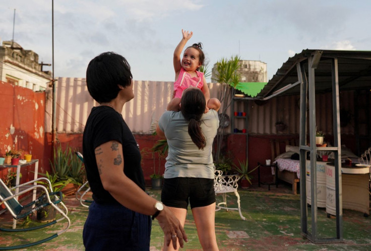A couple, Gabriela Alfonso Perez, 23, and Ria Acosta, 27, plays in their garden with Ria's daughter Ivelle Acosta, 2, in Havana, Cuba, July 13, 2022.