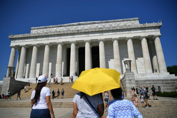 Visitors to the Lincoln Memorial use an umbrella to shelter from the Sun in Washington, DC, on July 23, 2022