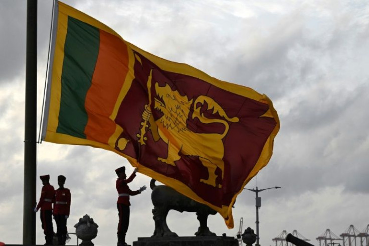Military personnel in ceremonial uniform lower the Sri Lanka national flag at Galle Face Green in Colombo