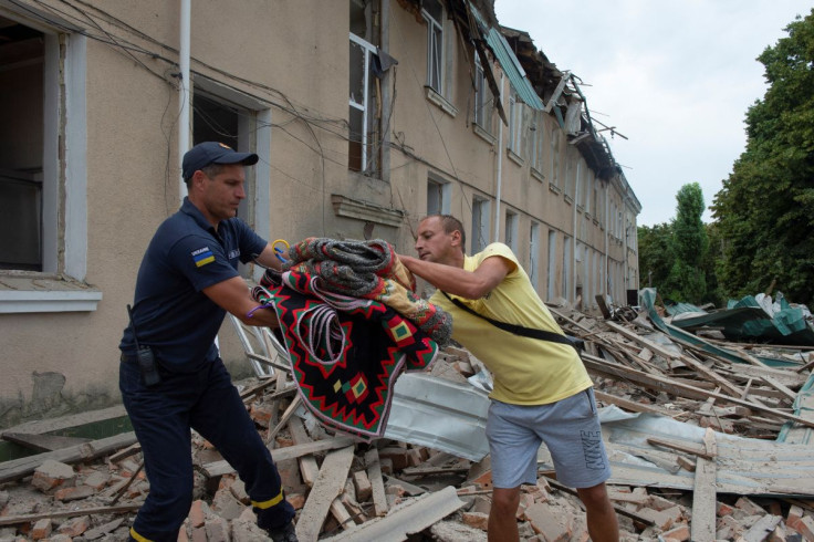 A rescuer passes to a man national Ukrainian clothes from the House of Culture building destroyed by a Russian missile strike, as Russia's attack on Ukraine continues, in the town of Chuhuiv, Kharkiv region, Ukraine July 25, 2022.  