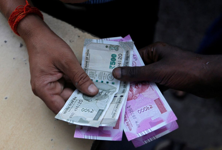 A customer hands Indian currency notes to an attendant at a fuel station in Mumbai, India, August 13, 2018. 