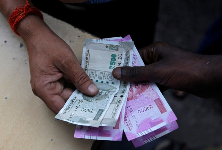 A customer hands Indian currency notes to an attendant at a fuel station in Mumbai, India, August 13, 2018.