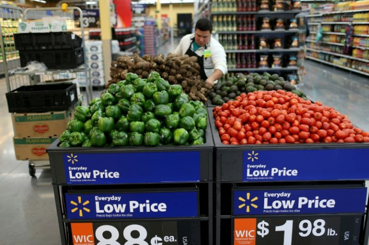 Consumers are spending more on food, gasoline and other essentials at Walmart, which cut its profit outlook because of the weakened forecast for other goods that are more lucrative