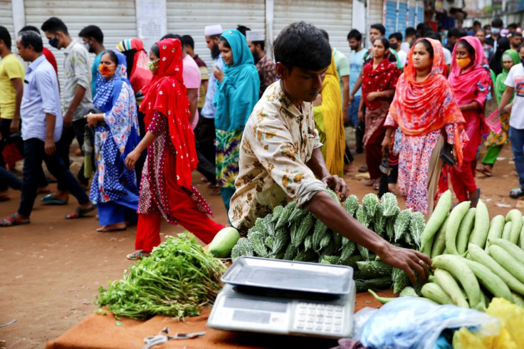 A man sells vegetables on the street while garment workers come out of a factory during the lunch break, as factories reamain open during a countrywide lockdown, in Dhaka, Bangladesh, July 6, 2021.