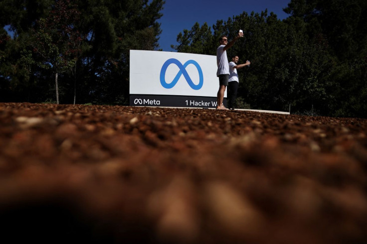 Men take selfies in front of a sign of Meta, the new name for the company formerly known as Facebook, at its headquarters in Menlo Park, California, U.S. October 28, 2021. 