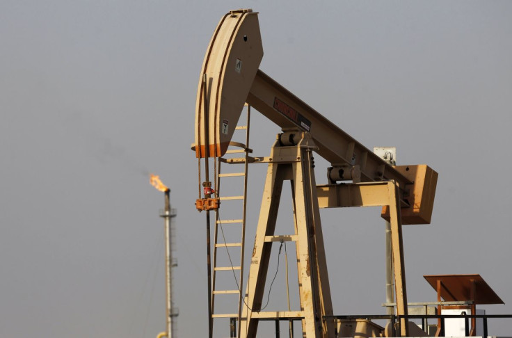 An oil pumping machine is seen as non-usable gases are being burnt behind it in Sakir, south of Manama,  October 11, 2014. 