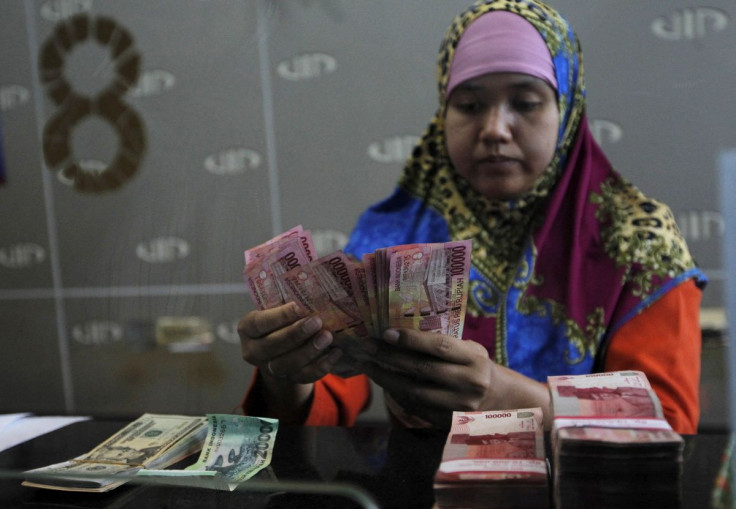 A teller counts Indonesian rupiah notes for a customer at a money changer in Jakarta, Indonesia, August 26, 2015. Indonesia's central bank has urged exporters and businesses not to hoard foreign currency as part of its effort to maintain financial stabili