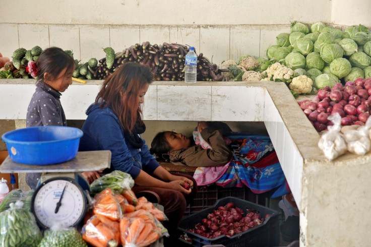 A girl checks her mobile phone as her mother prepares vegetables at market in the capital city of Thimphu, Bhutan, December 11, 2017.