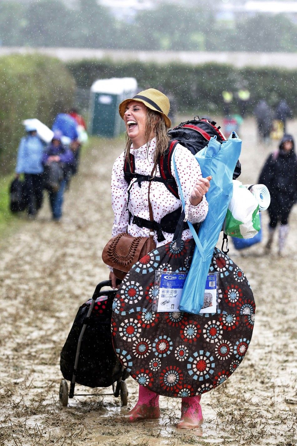 Glastonbury 2011 Revellers tread muddy fields to celebrate event.